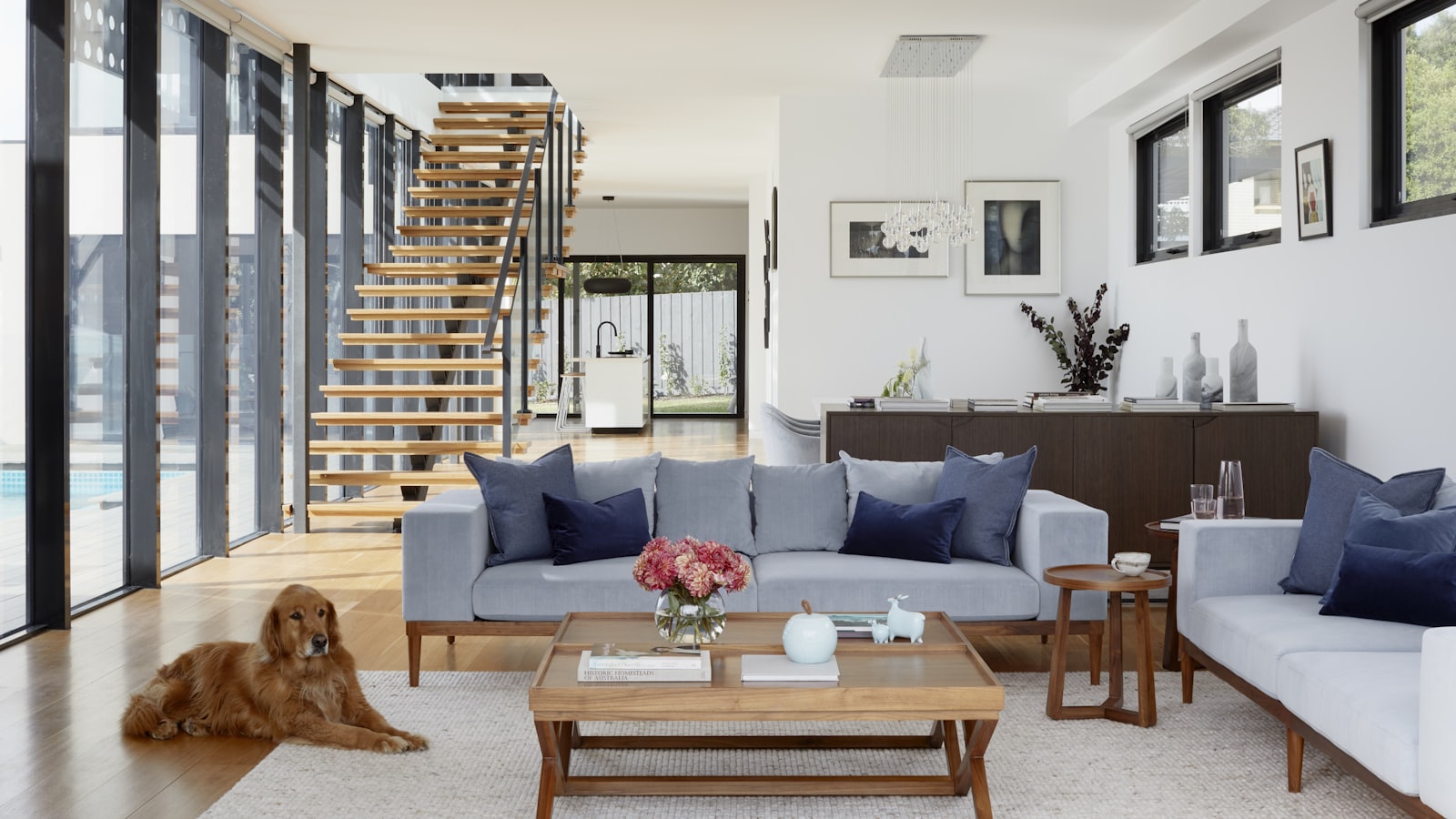 A rustic living room with exposed wood beams, a stone fireplace, a chunky knit throw, and soft natural light