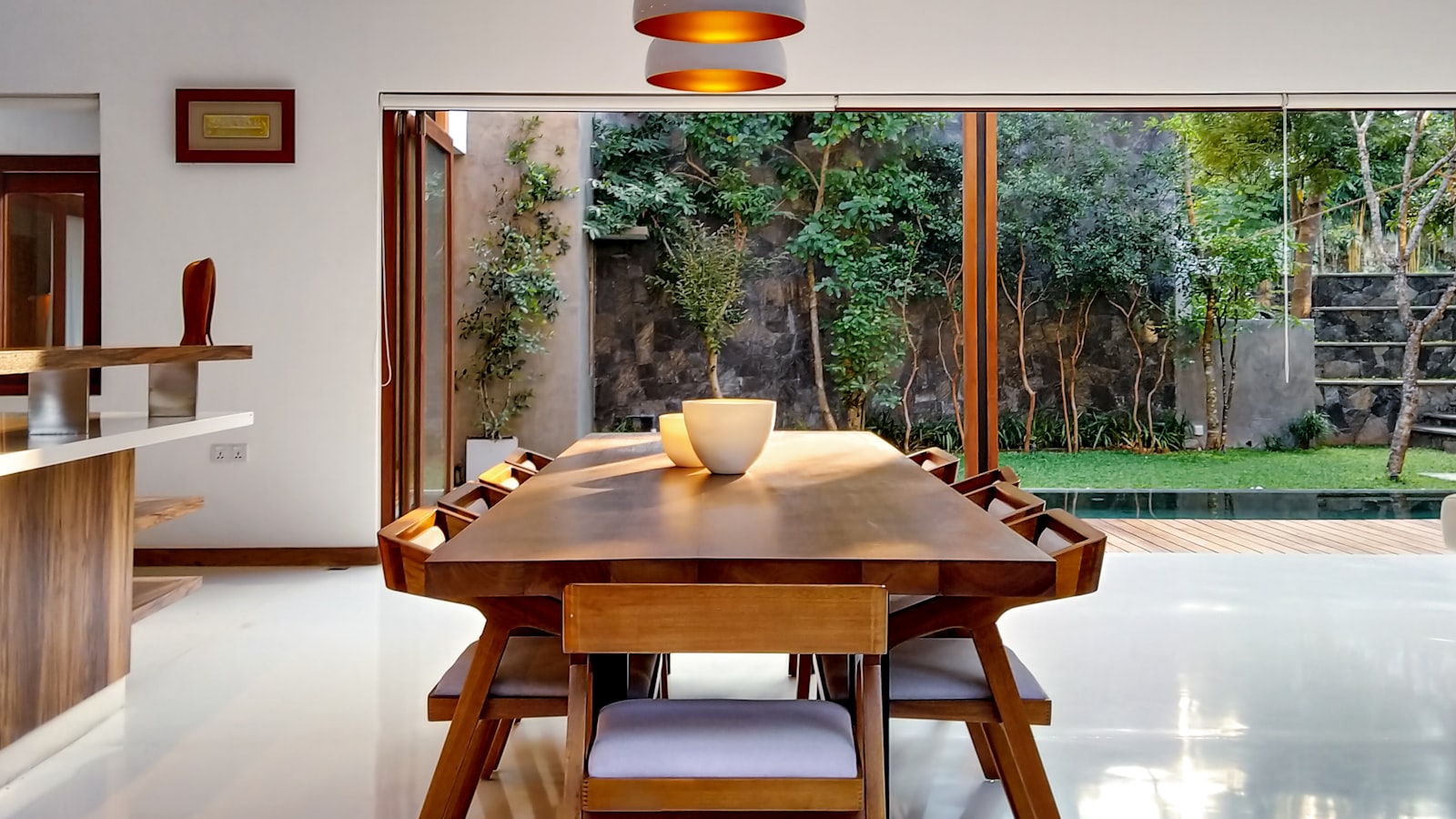 A vibrant living space with a deep blue wall, warm wood furniture, and colorful cushions and art.